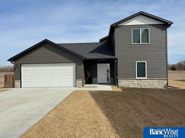 view of front of home with a shingled roof, a front lawn, concrete driveway, stone siding, and an attached garage