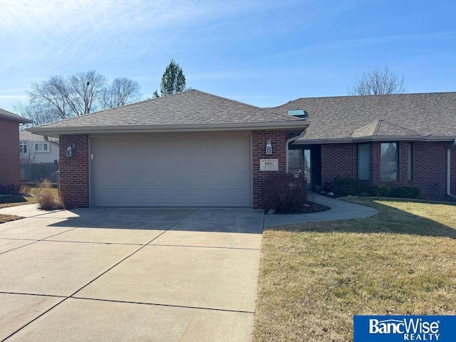 view of front of house with a front lawn, concrete driveway, a shingled roof, a garage, and brick siding