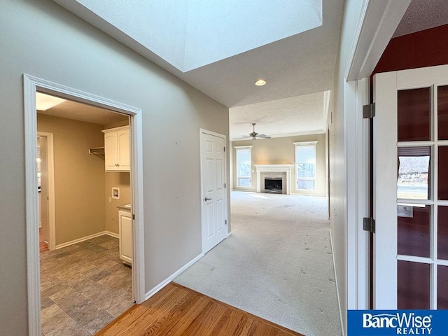 hall featuring baseboards and light carpet