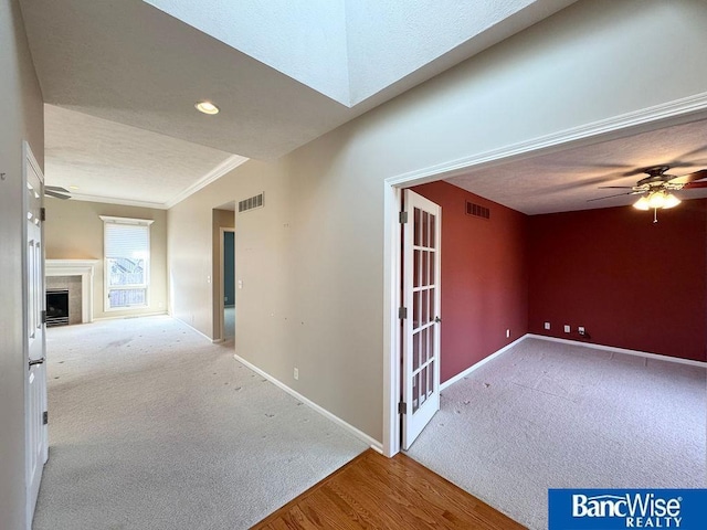 interior space featuring carpet flooring, baseboards, visible vents, and ornamental molding