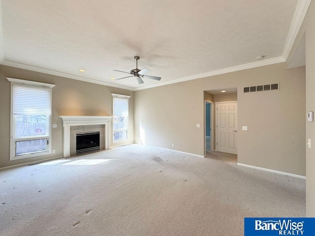 unfurnished living room with carpet, baseboards, visible vents, a tiled fireplace, and crown molding