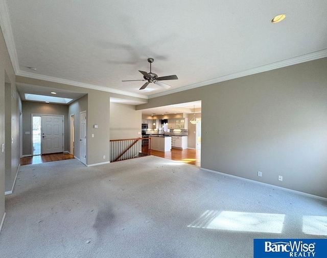 unfurnished living room with ceiling fan, carpet, baseboards, and ornamental molding