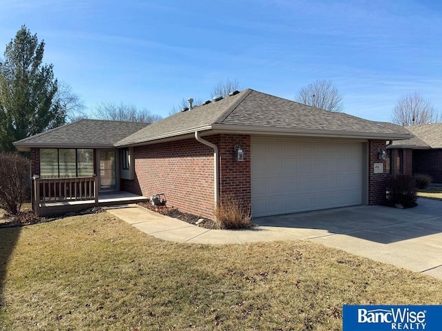 view of side of home with a yard, a shingled roof, concrete driveway, a garage, and brick siding