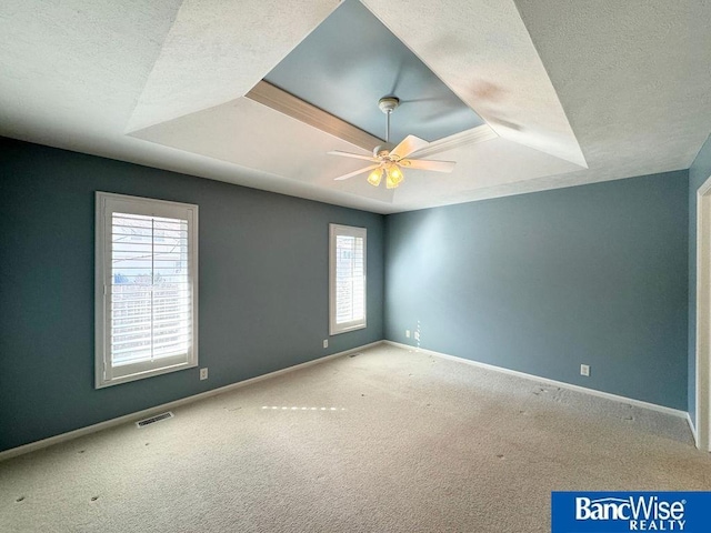 carpeted empty room featuring visible vents, baseboards, ceiling fan, a tray ceiling, and a textured ceiling