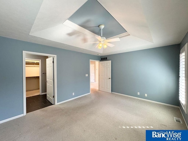 unfurnished bedroom featuring a raised ceiling, baseboards, visible vents, and carpet floors