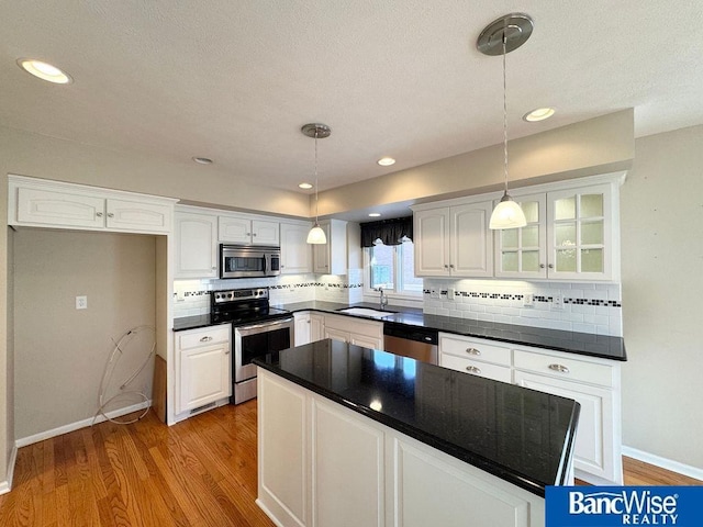 kitchen featuring a sink, stainless steel appliances, light wood-type flooring, and white cabinetry