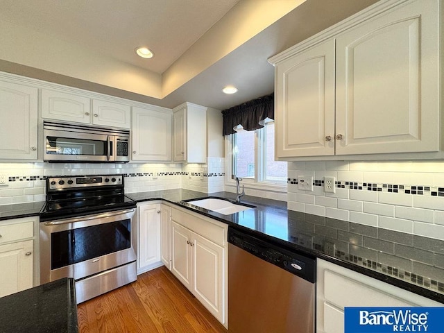 kitchen featuring a sink, light wood-type flooring, appliances with stainless steel finishes, and white cabinets