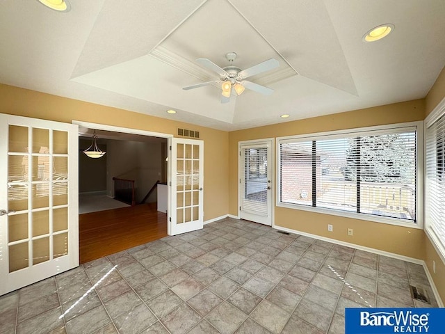 spare room featuring recessed lighting, french doors, a raised ceiling, and baseboards