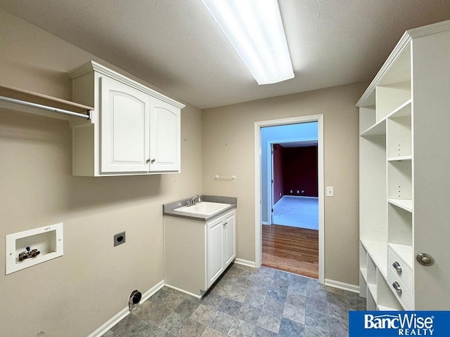 washroom featuring baseboards, hookup for a washing machine, cabinet space, hookup for an electric dryer, and a sink