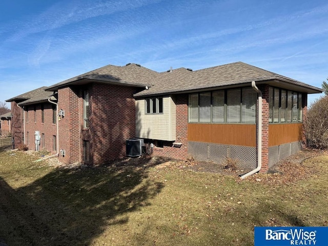 view of side of home with brick siding, a lawn, and a shingled roof