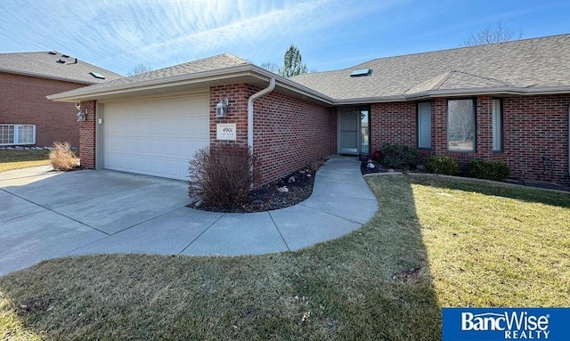 single story home with roof with shingles, concrete driveway, a front yard, a garage, and brick siding