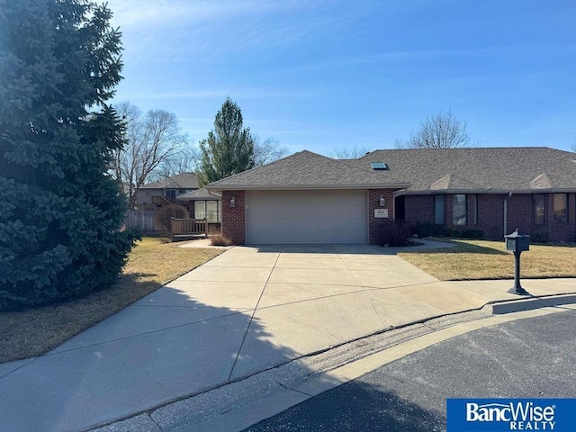 ranch-style house with a front lawn, brick siding, concrete driveway, and an attached garage