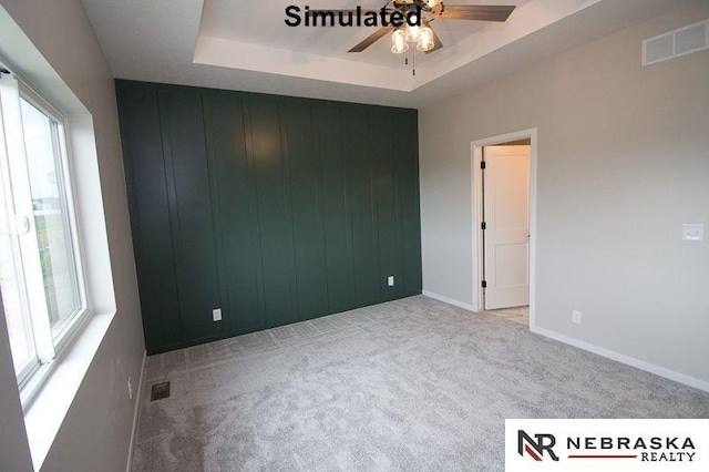 spare room featuring visible vents, a raised ceiling, plenty of natural light, and carpet