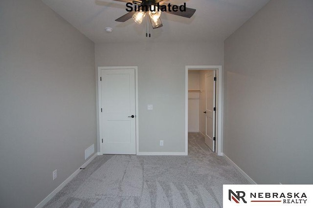 unfurnished bedroom with a spacious closet, baseboards, carpet, a closet, and a ceiling fan