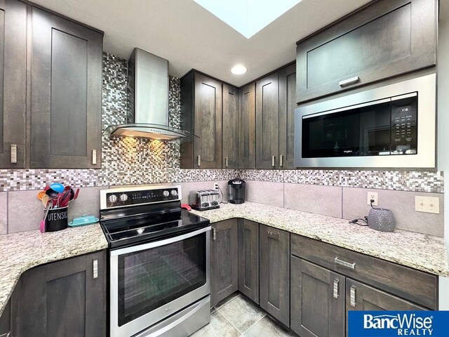 kitchen featuring decorative backsplash, wall chimney exhaust hood, electric stove, and built in microwave