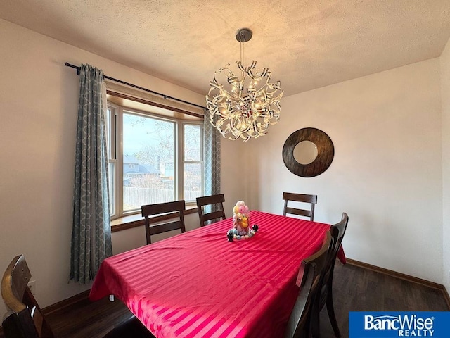 dining area featuring an inviting chandelier, a textured ceiling, baseboards, and wood finished floors