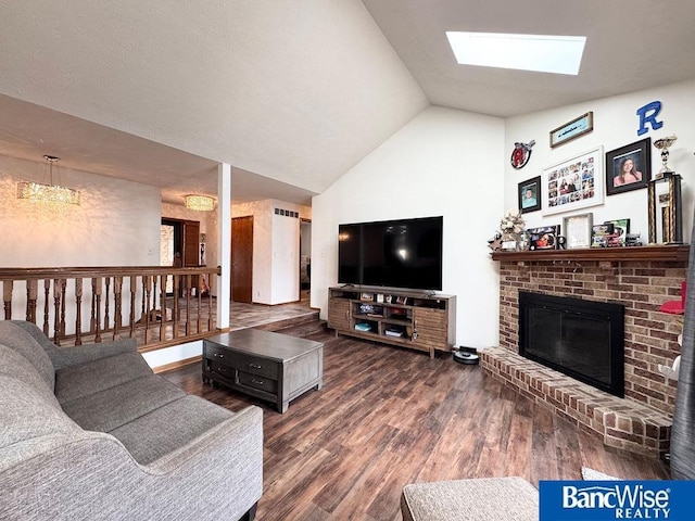 living room with visible vents, lofted ceiling with skylight, wood finished floors, and a fireplace