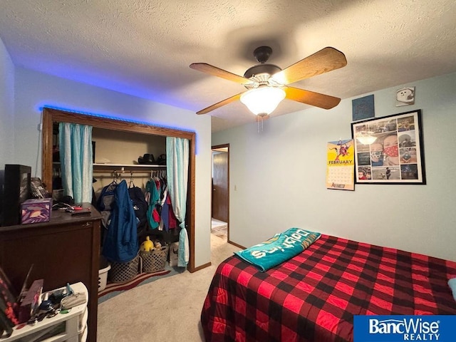 bedroom featuring a closet, light colored carpet, ceiling fan, and a textured ceiling