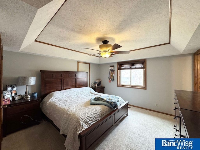 bedroom featuring a textured ceiling, a tray ceiling, baseboards, and light carpet