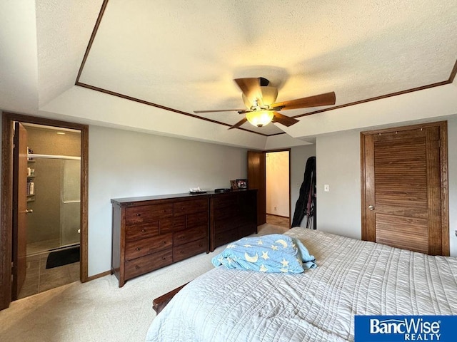 bedroom with ensuite bathroom, light colored carpet, a ceiling fan, and a textured ceiling