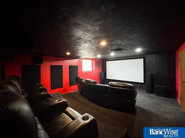 carpeted home theater room with visible vents and a textured ceiling