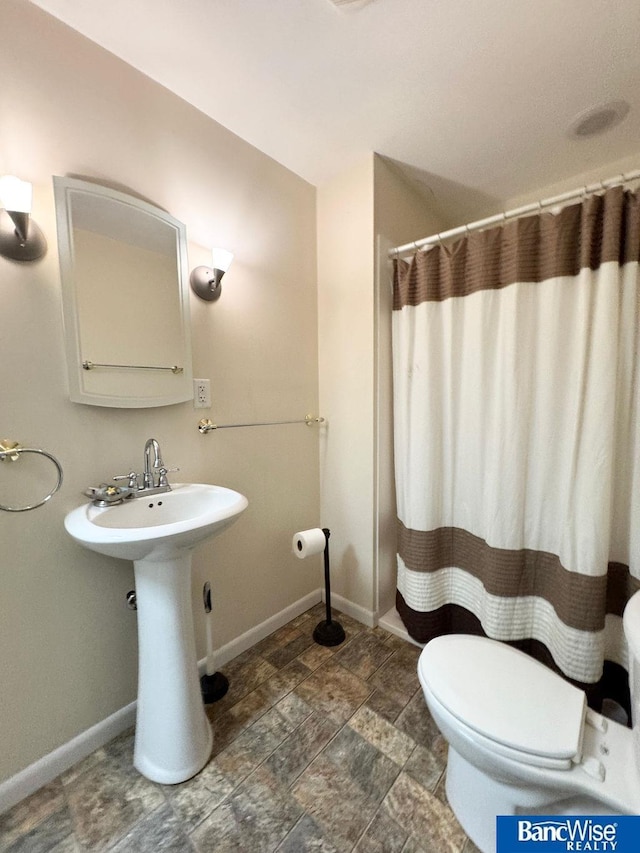 full bathroom with curtained shower, toilet, baseboards, and a sink