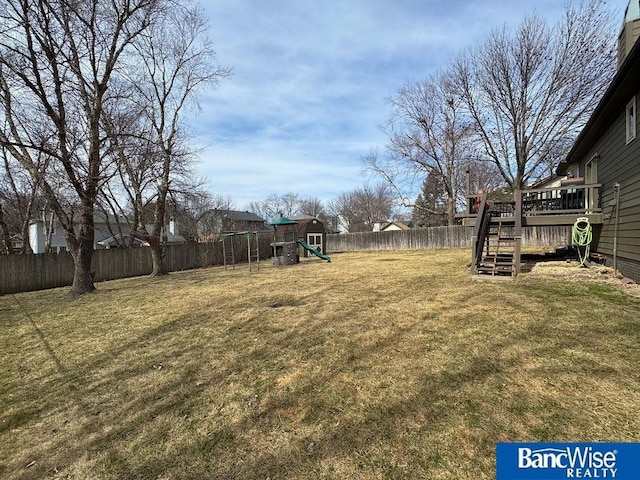 view of yard with a deck, a fenced backyard, stairs, and a playground