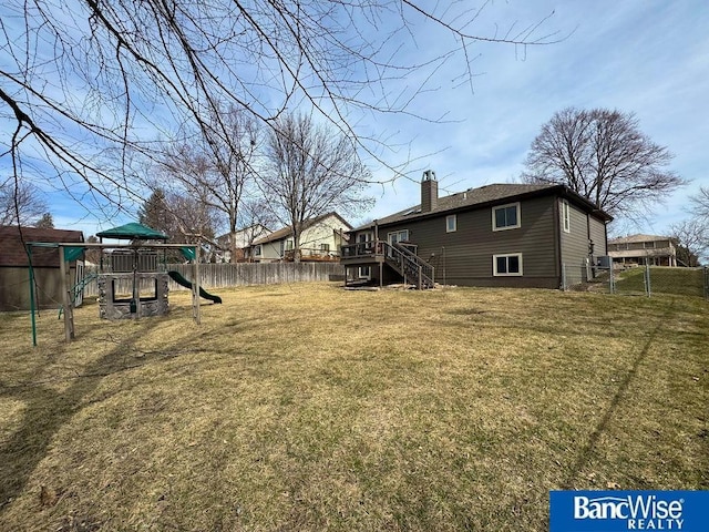 view of yard featuring a deck, stairway, a playground, and fence