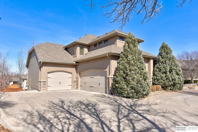 view of side of property with concrete driveway, stone siding, and stucco siding