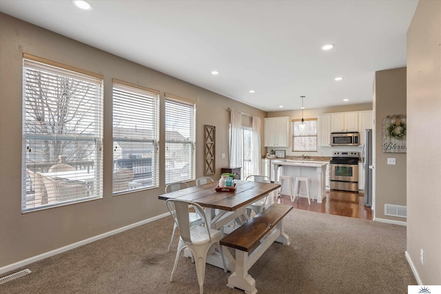 carpeted dining area featuring recessed lighting, visible vents, baseboards, and plenty of natural light