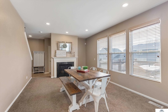 dining area featuring a high end fireplace, visible vents, baseboards, light colored carpet, and recessed lighting