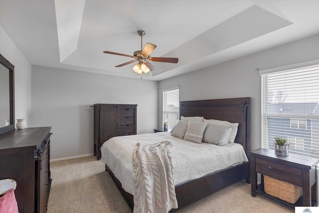 bedroom featuring a ceiling fan, a raised ceiling, light colored carpet, and baseboards