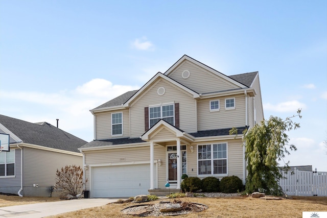 traditional-style house with an attached garage, driveway, and fence