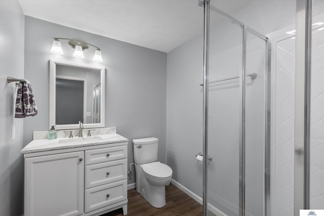 full bath featuring toilet, a stall shower, wood finished floors, baseboards, and vanity