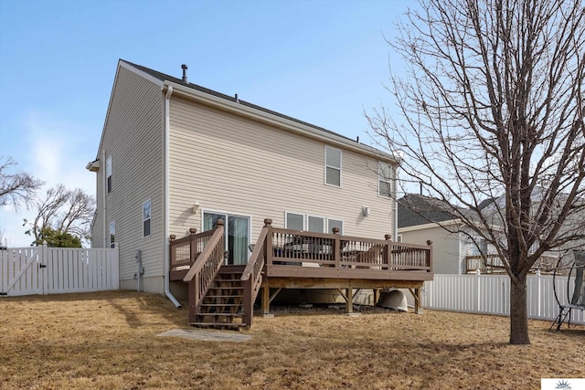 rear view of house featuring a deck, a gate, a fenced backyard, and a yard