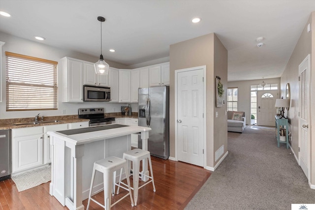 kitchen featuring a sink, a kitchen island, white cabinetry, and stainless steel appliances