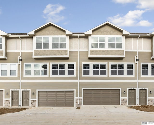 view of property featuring stone siding, driveway, and a garage