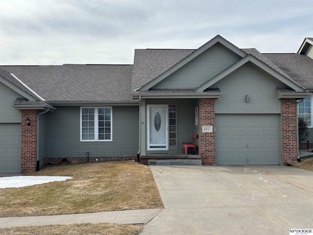 single story home featuring concrete driveway, an attached garage, brick siding, and a shingled roof