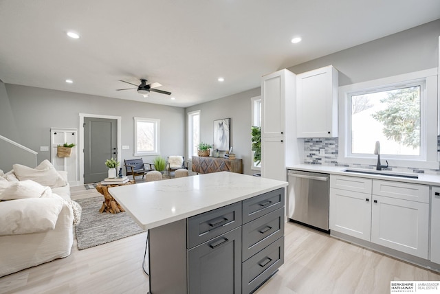 kitchen featuring a sink, dishwasher, open floor plan, and white cabinets