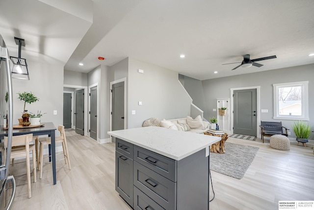 kitchen with light wood finished floors, a kitchen island, open floor plan, gray cabinets, and recessed lighting