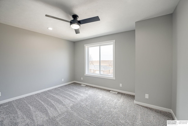 unfurnished room with carpet, visible vents, baseboards, ceiling fan, and a textured ceiling