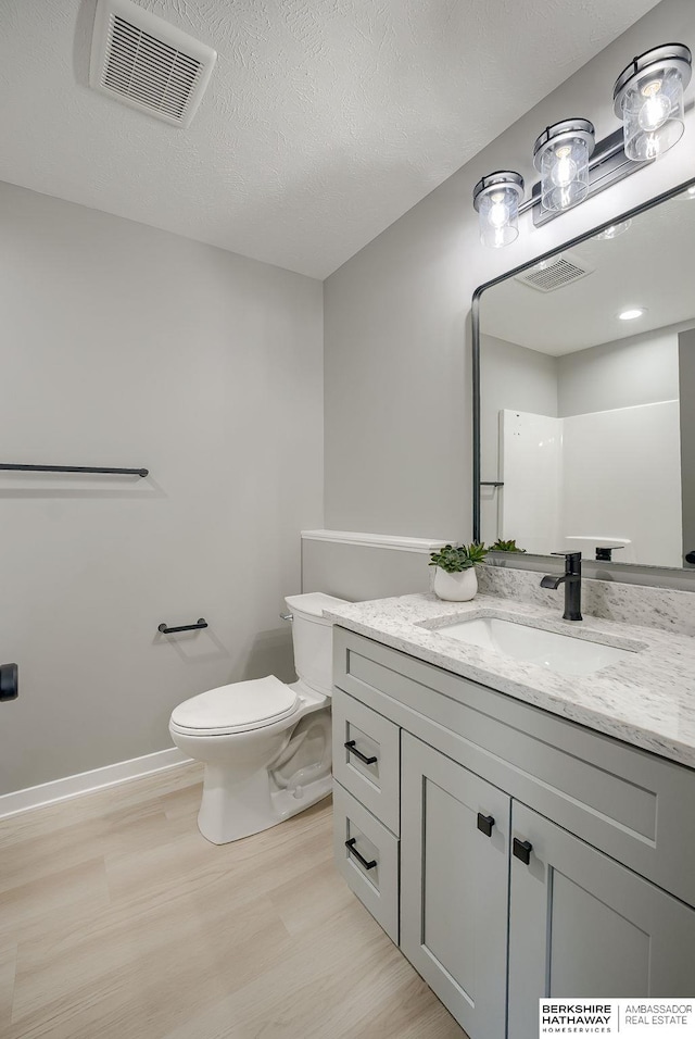 bathroom featuring vanity, toilet, wood finished floors, and visible vents