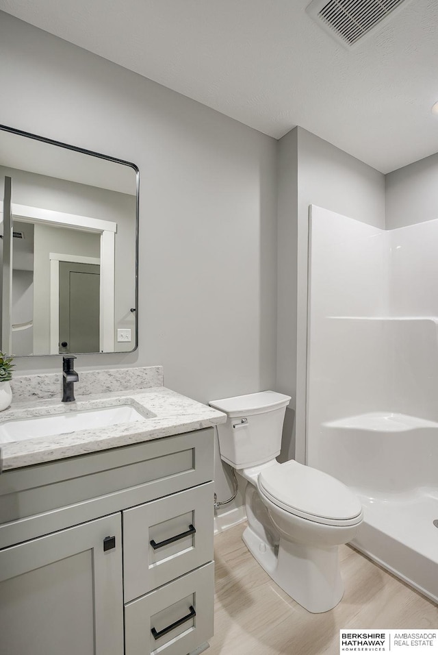 bathroom with a shower, visible vents, toilet, and vanity