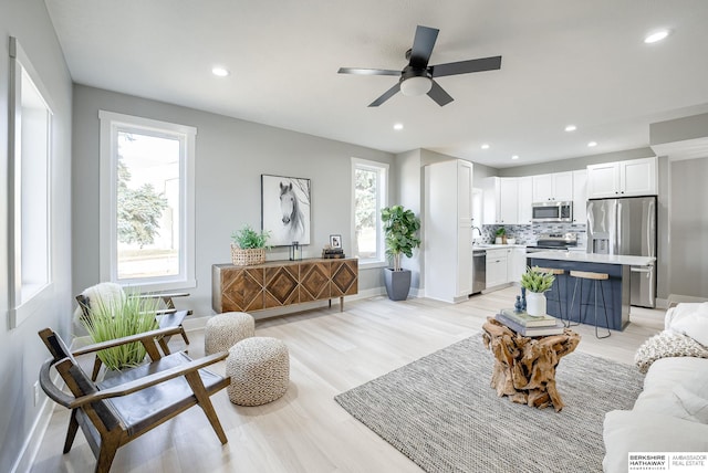 living room featuring a ceiling fan, recessed lighting, light wood-type flooring, and baseboards