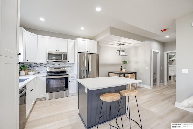 kitchen featuring a breakfast bar, a kitchen island, tasteful backsplash, stainless steel appliances, and white cabinets