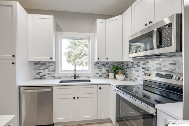 kitchen with decorative backsplash, white cabinetry, stainless steel appliances, and a sink