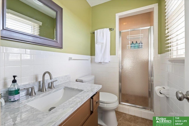 bathroom featuring vanity, a shower stall, toilet, and tile walls