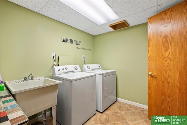 laundry area featuring baseboards, laundry area, separate washer and dryer, light tile patterned flooring, and a sink