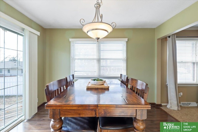 dining space with a wealth of natural light, visible vents, baseboards, and wood finished floors