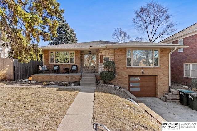 view of front of property with a garage, brick siding, driveway, and fence